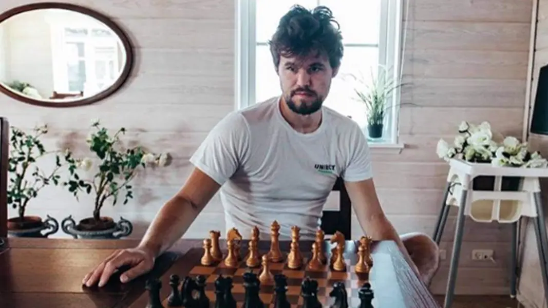 Magnus Carlsen sits by a chess board