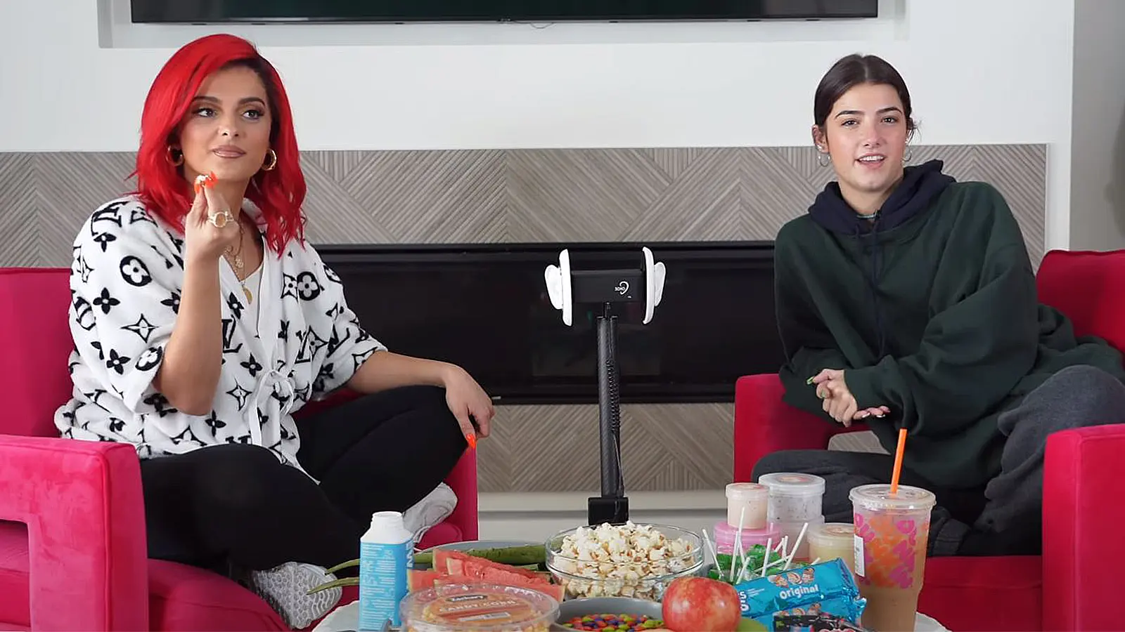 Charli D'Amelio and Bebe Rexha sit in front of a spread of candy and an ASMR mic.