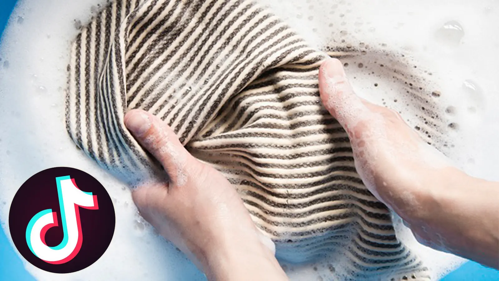 A pair of hands is shown washing clothes in a bucket.