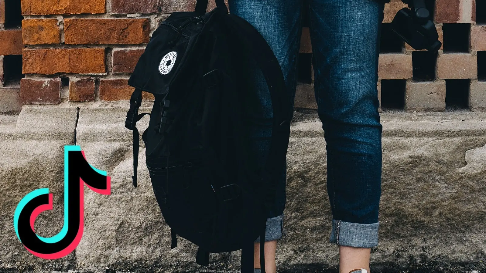 A person stands with a bag next to the TikTok logo