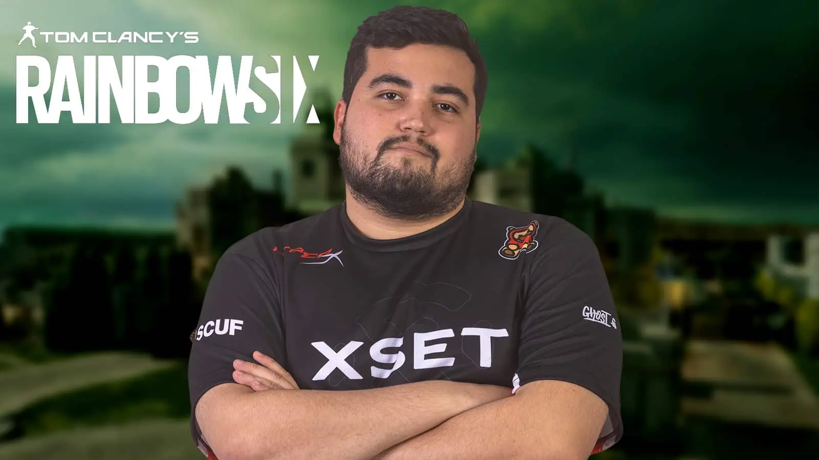 XSET Rainbow Six coach Budega on blurred background with Rainbow Six logo in corner