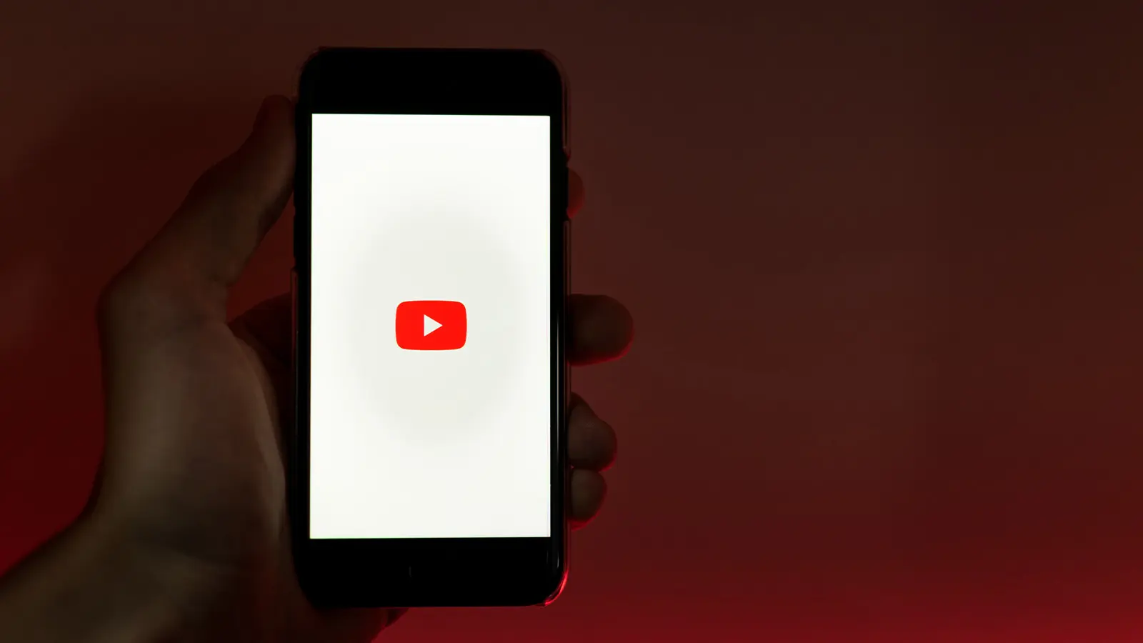 hand holding a phone with the YouTube logo on it