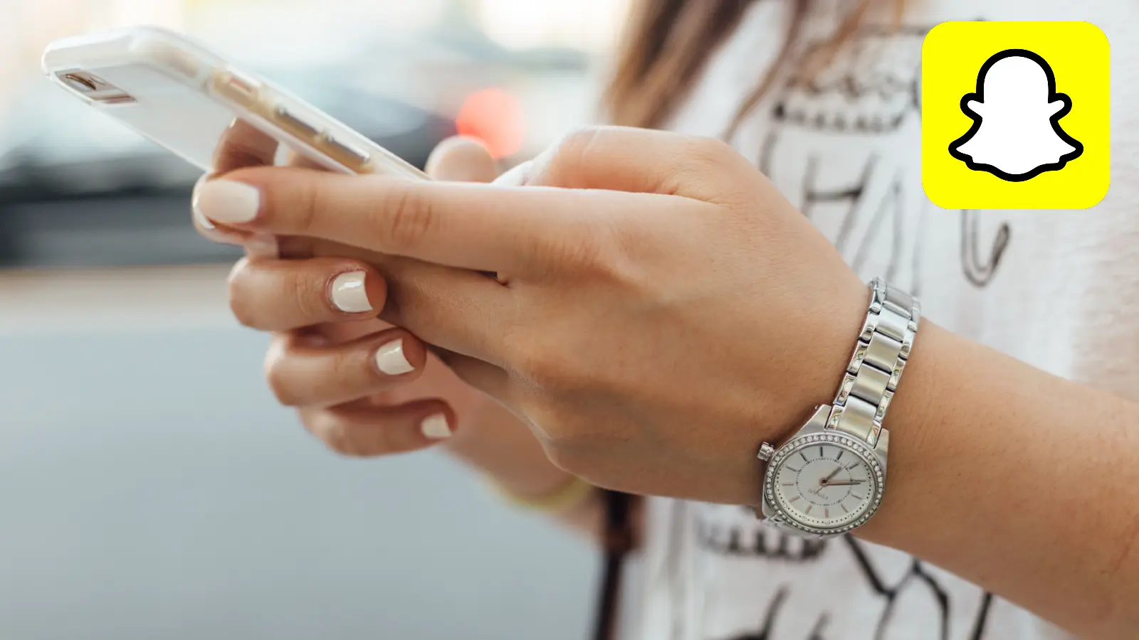 Snapchat logo next to person holding phone