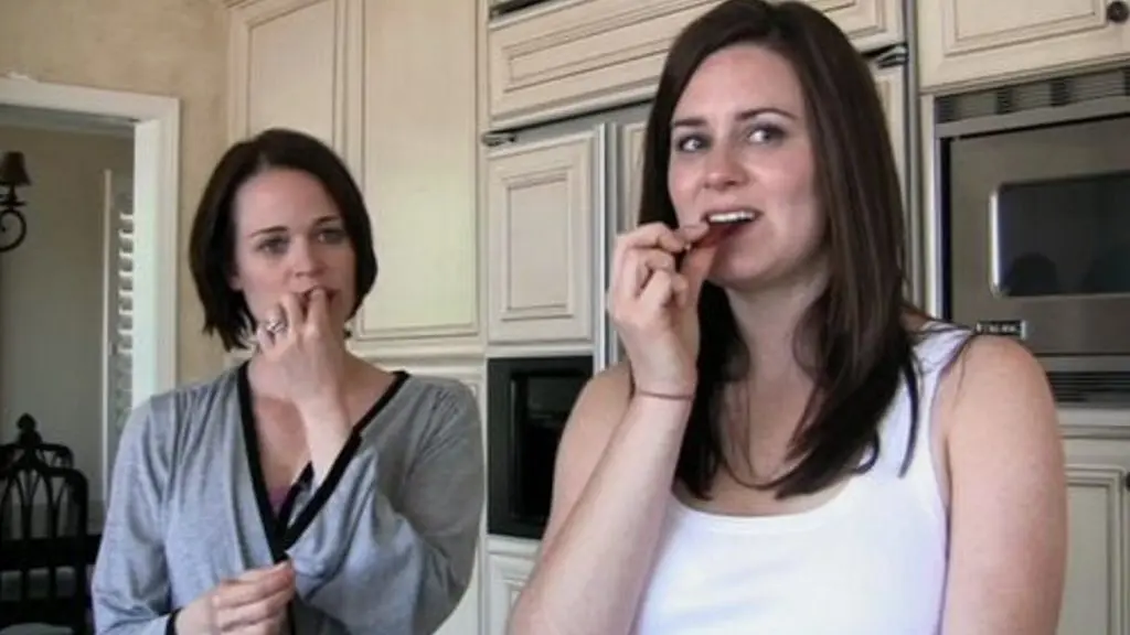 Katie and Kristi stand side by side eating candy