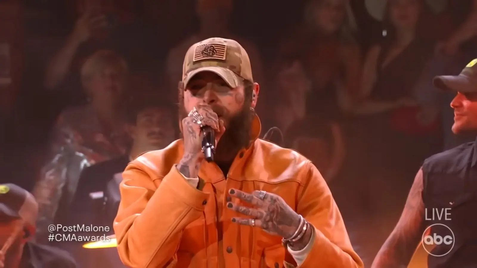 Post Malone performs in an orange outfit at the CMA Awards