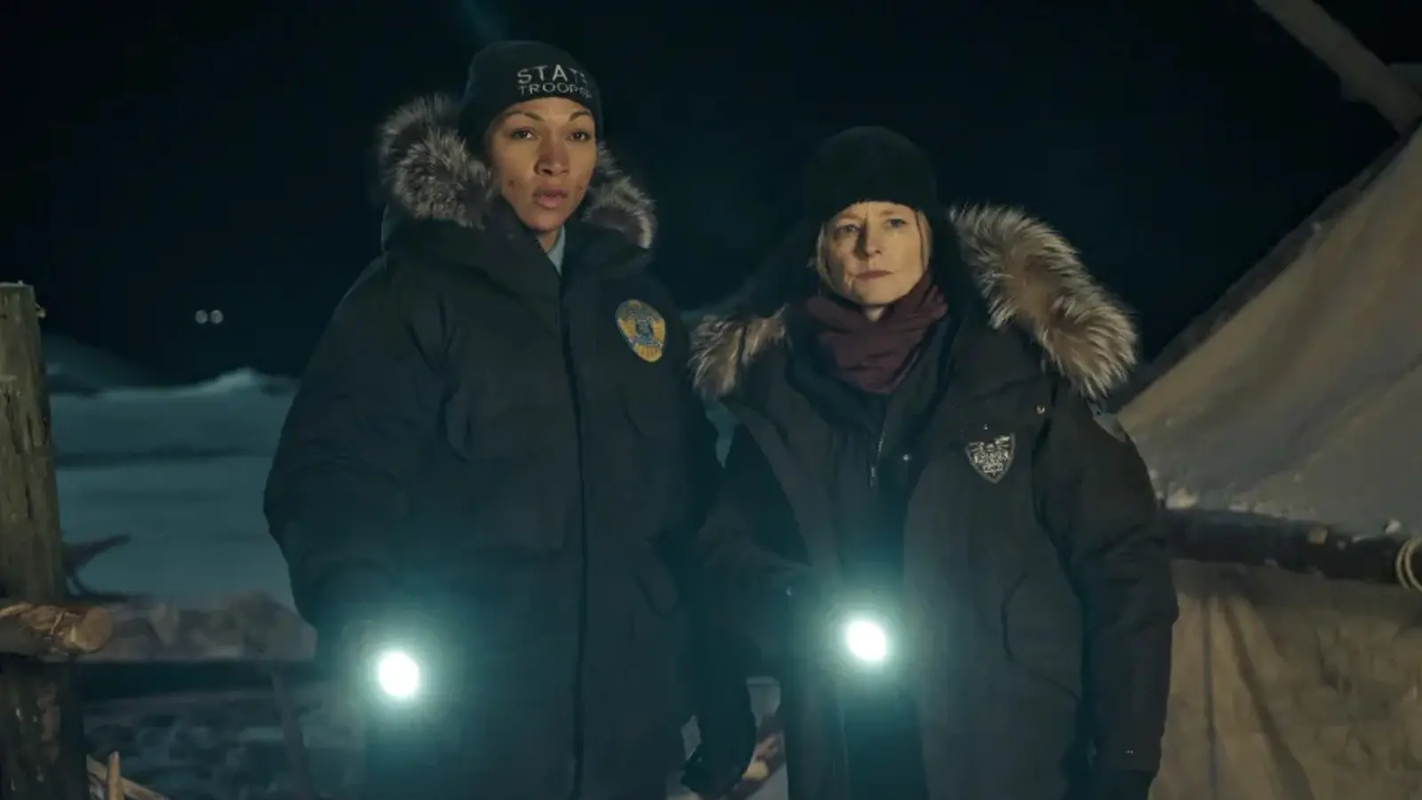 Kali Reis and Jodie Foster as detectives holding torches in True Detective Season 4.