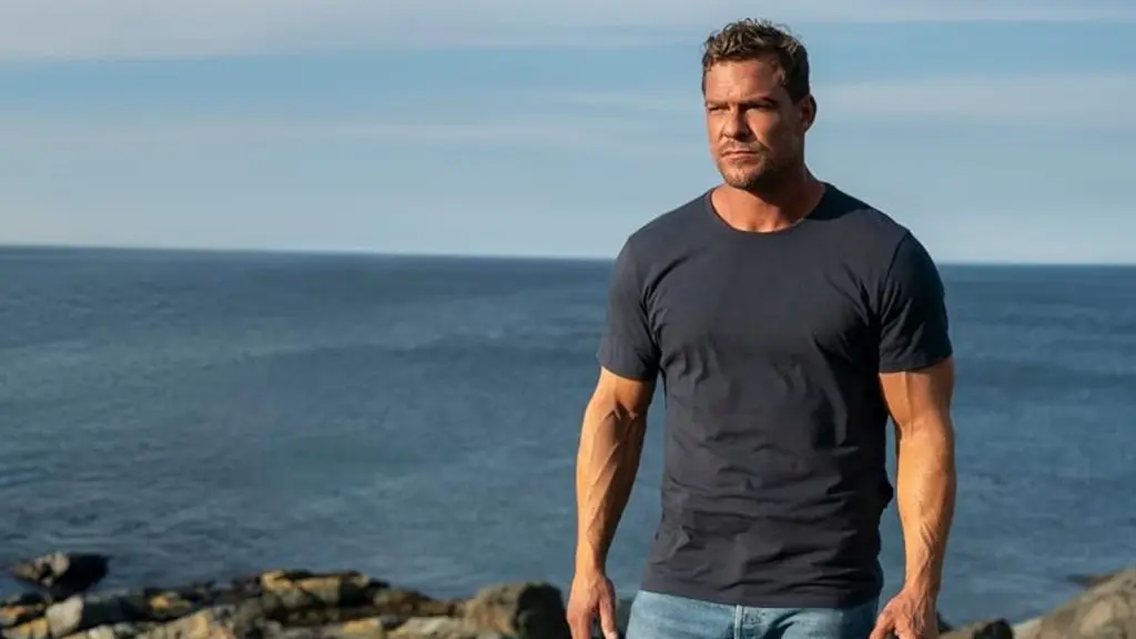 Alan Ritchson standing near the ocean in Reacher.