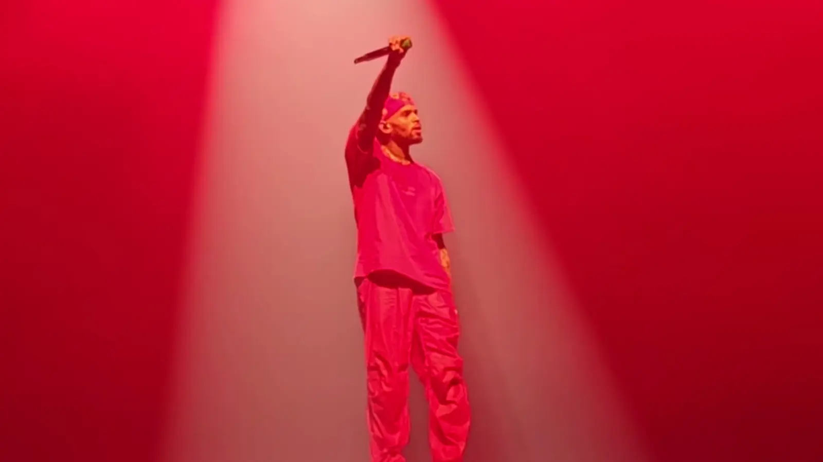 Chris Brown performing in red light on a stage in London