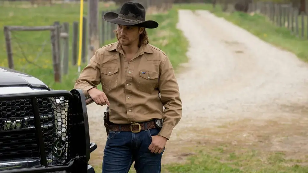 Luke Grimes as Kayce Dutton in Yellowstone, leaning against a truck