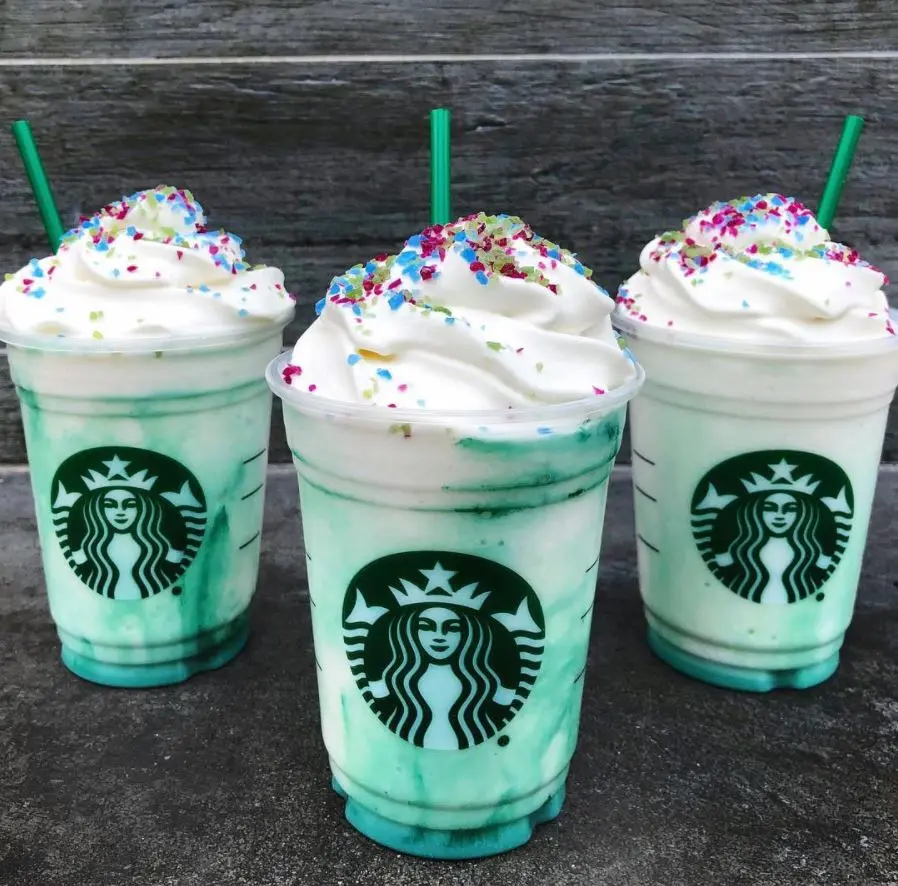 Three blue swirled starbucks frappuccionos with cream on top