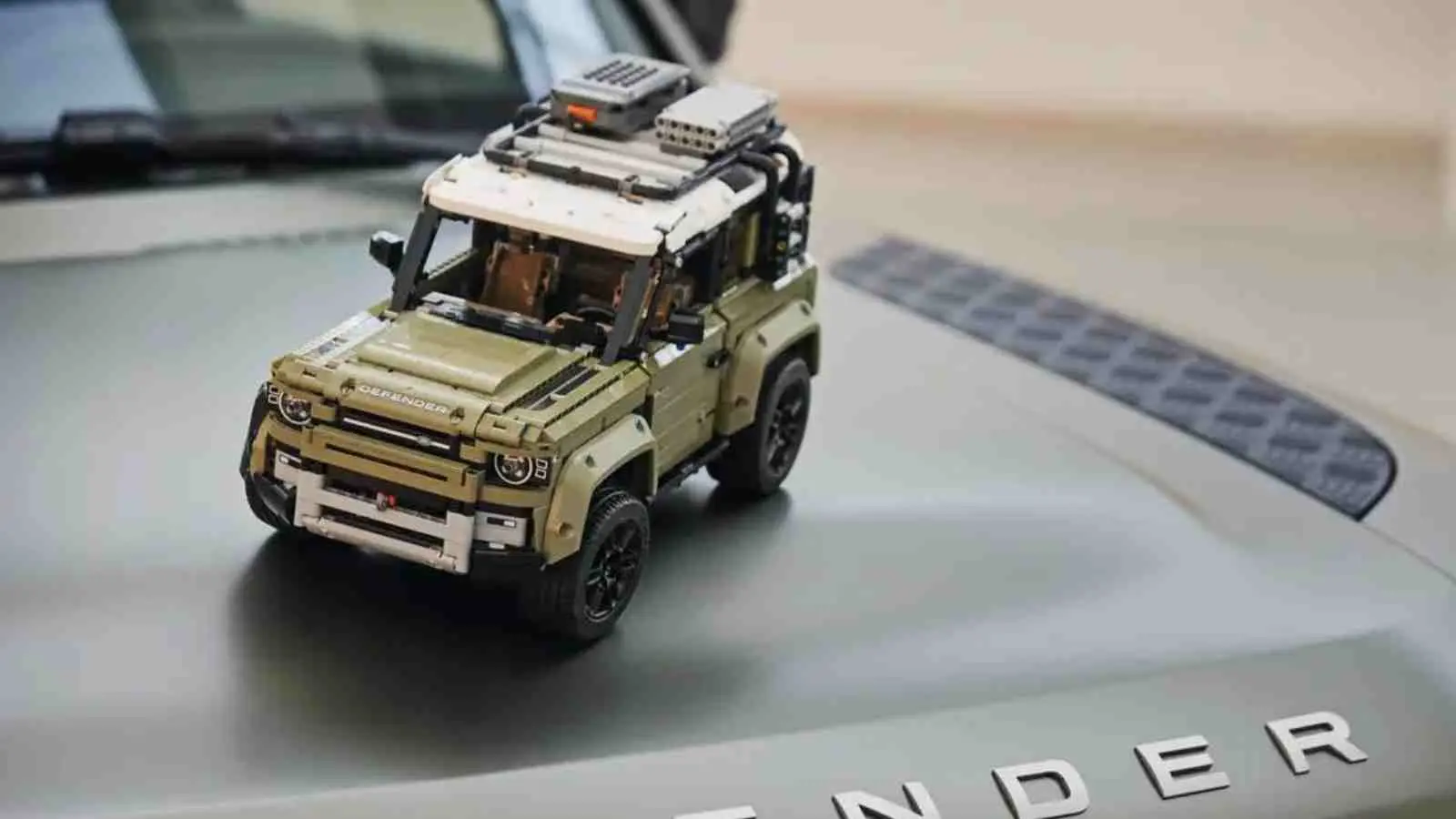 The LEGO Technic Land Rover Defender on the hood of the real-life Defender