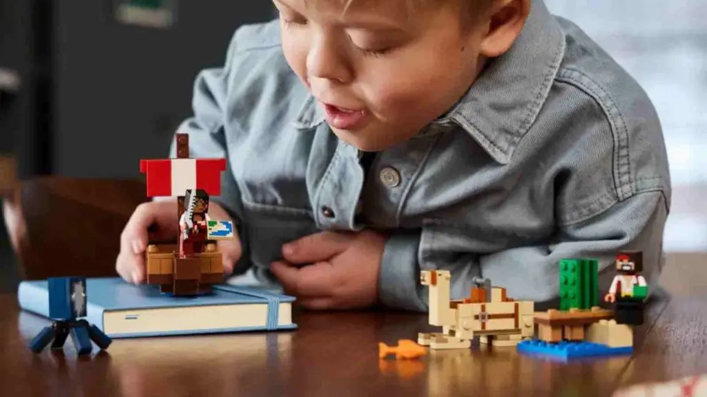 A child with their brick-built Minecraft pirate ship