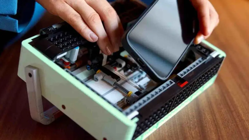 An adult placing their smartphone into the LEGO-reimagined radio