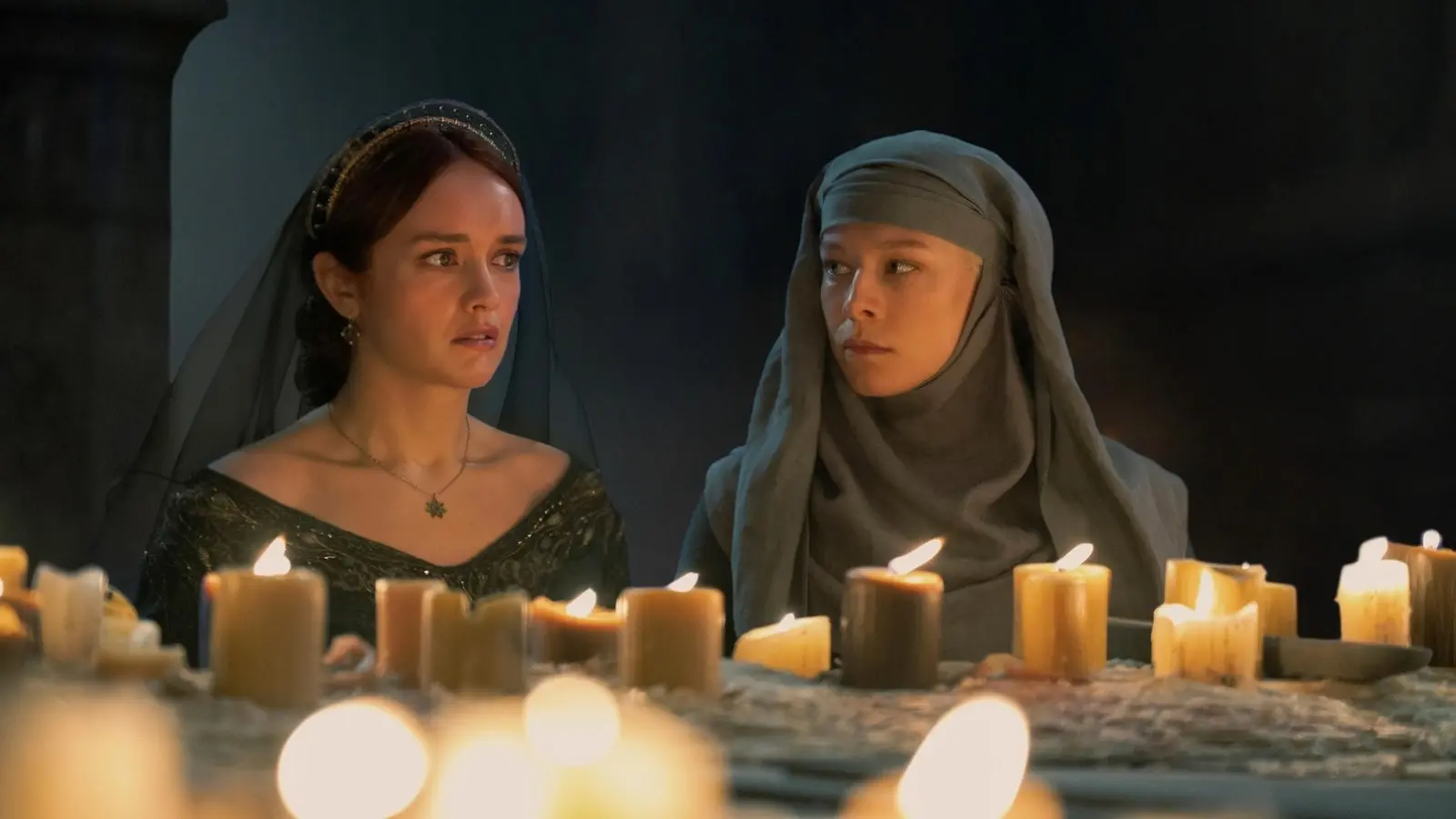 Olivia Cooke and Emma D'Arcy as Alicent and Rhaenyra in the Sept, lit by candles