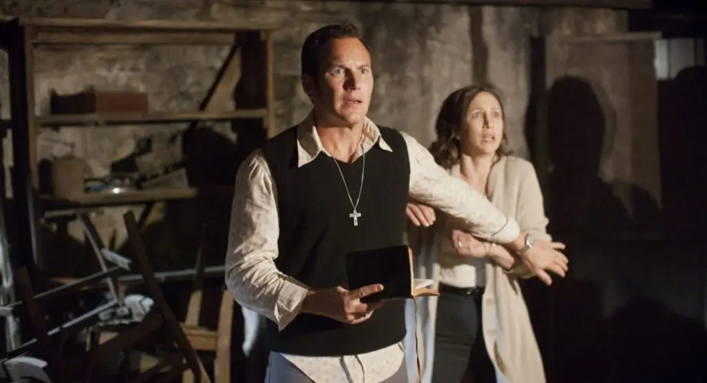 Vera Farmiga and Patrick Wilson as Lorraine and Ed Warren in The Conjuring, with Ed holding a bible