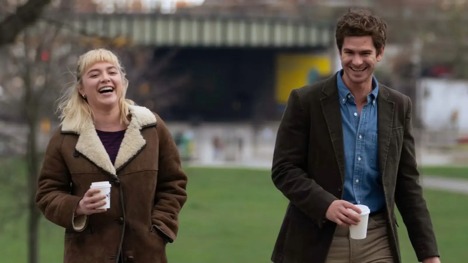 Florence Pugh and Andrew Garfield as Tobias and Almut in We Live in Time, walking through the park and laughing