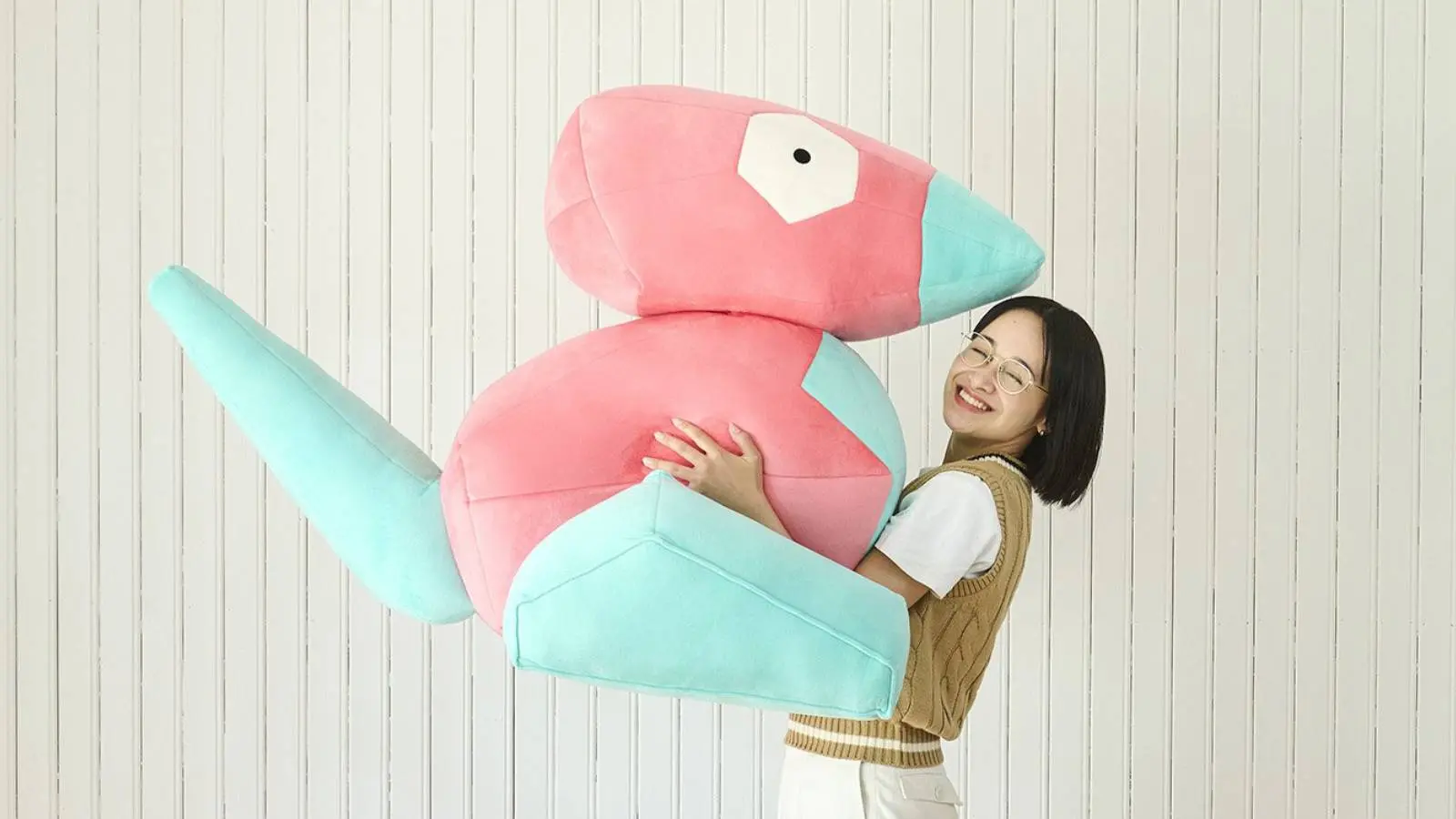 A person holds up a life size Porygon plush