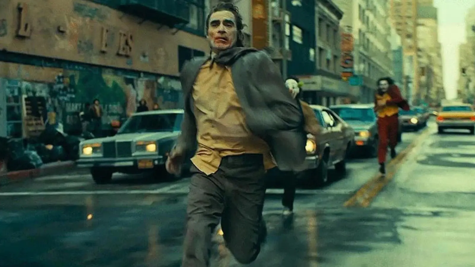 Joaquin Phoenix chased down the street by masked men in suits in the Joker 2 ending