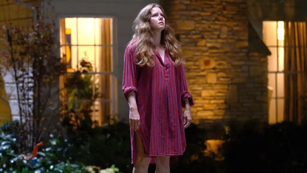 Amy Adams standing outside her house in Nightbitch.