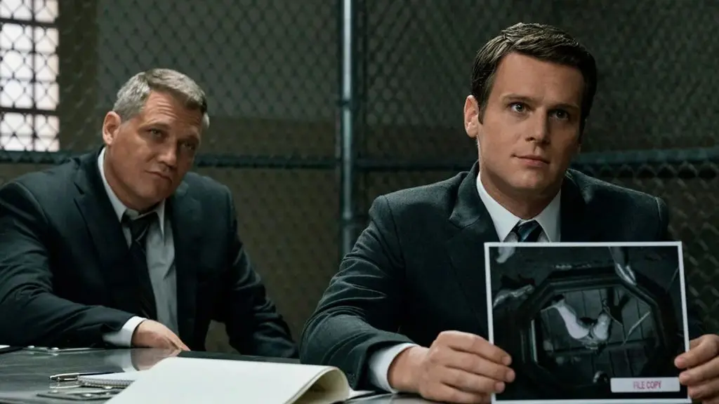 Holden Ford (Jonathan Groff), Bill Tench (Holt McCallany) sitting behind a desk in Mindhunter.