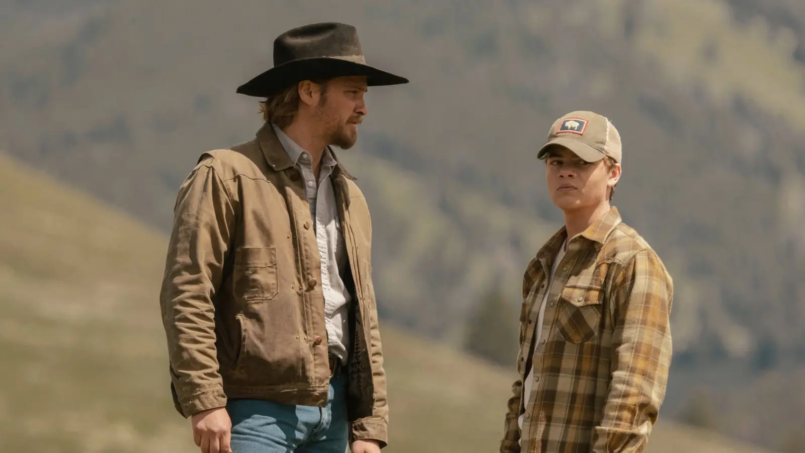 Luke Grimes as Kayce in Yellowstone, standing with Tate