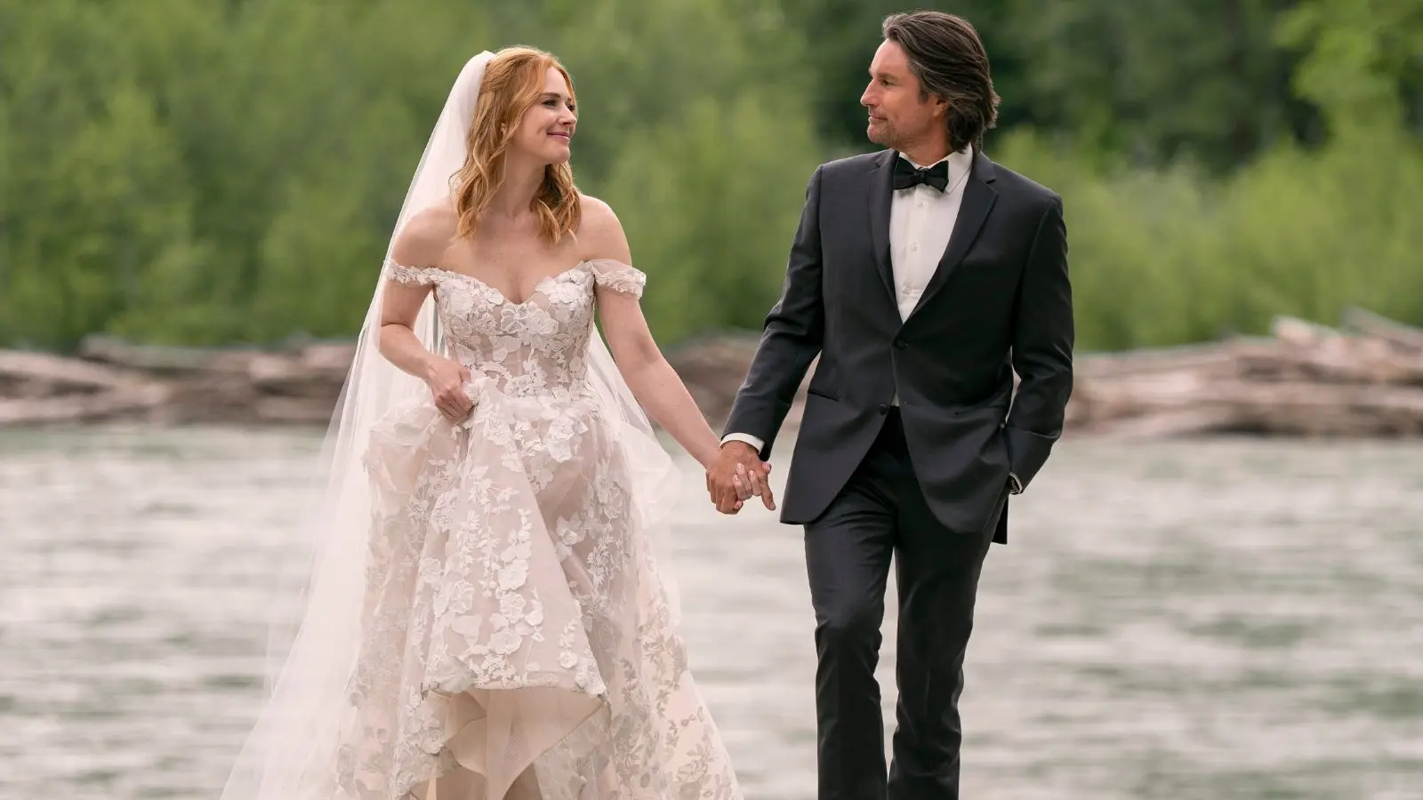 Mel and Jack walk hand in hand on the river in their wedding outfits in Virgin River Season 6